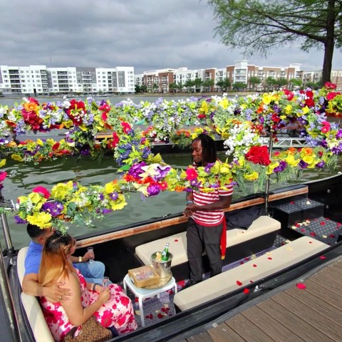 People sitting on a boat decorated with colorful flowers on a river.